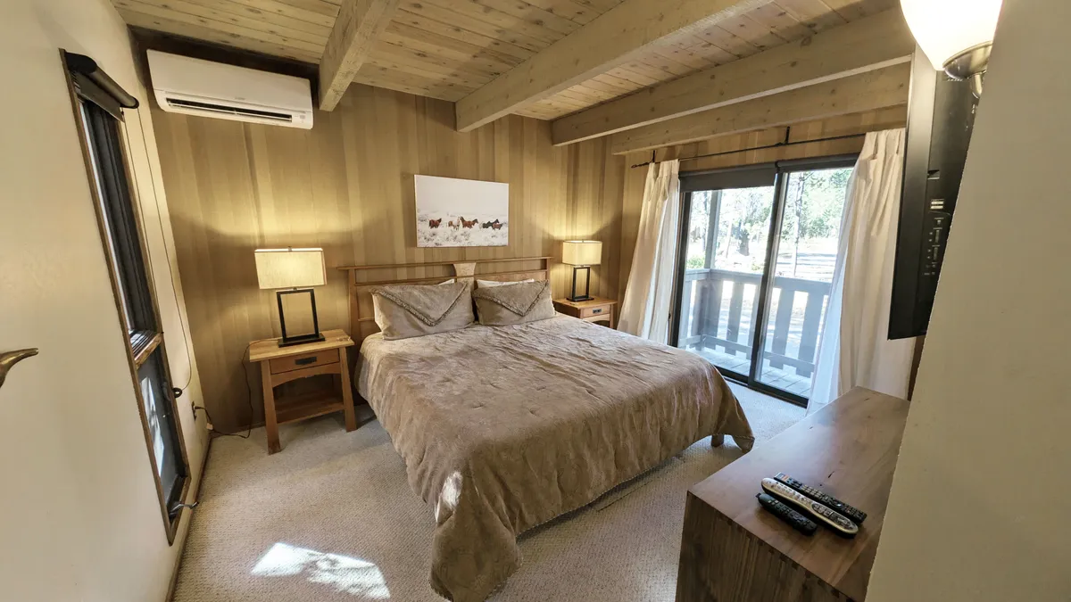 A serene bedroom scene featuring a plush king bed, flanked by elegant nightstands and topped with inviting bedding. Soft sunlight filters through a window, illuminating tasteful artwork and creating a tranquil atmosphere perfect for rest and relaxation.